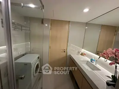 Modern bathroom with washing machine and elegant vanity in sleek apartment.