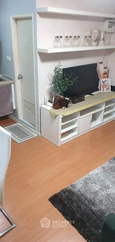 Modern living room with stylish decor and wooden flooring, featuring a sleek entertainment unit and cozy ambiance.