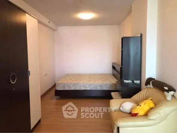 Cozy bedroom with wooden flooring and comfortable seating area.