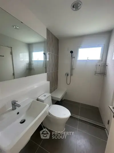 Modern bathroom with sleek fixtures and natural light, featuring a spacious shower area and contemporary design.