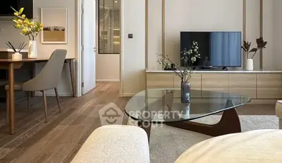 Modern living room with stylish furniture and large TV, featuring elegant decor and wooden flooring.