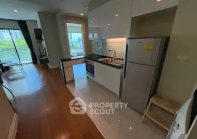 Modern open-layout kitchen with sleek appliances and bright living area in a stylish apartment.