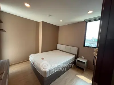 Spacious bedroom with large window and modern furnishings in a stylish apartment.