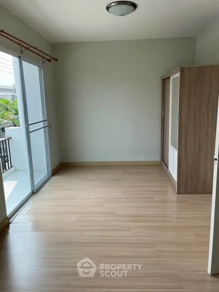 Spacious bedroom with wooden flooring and balcony access