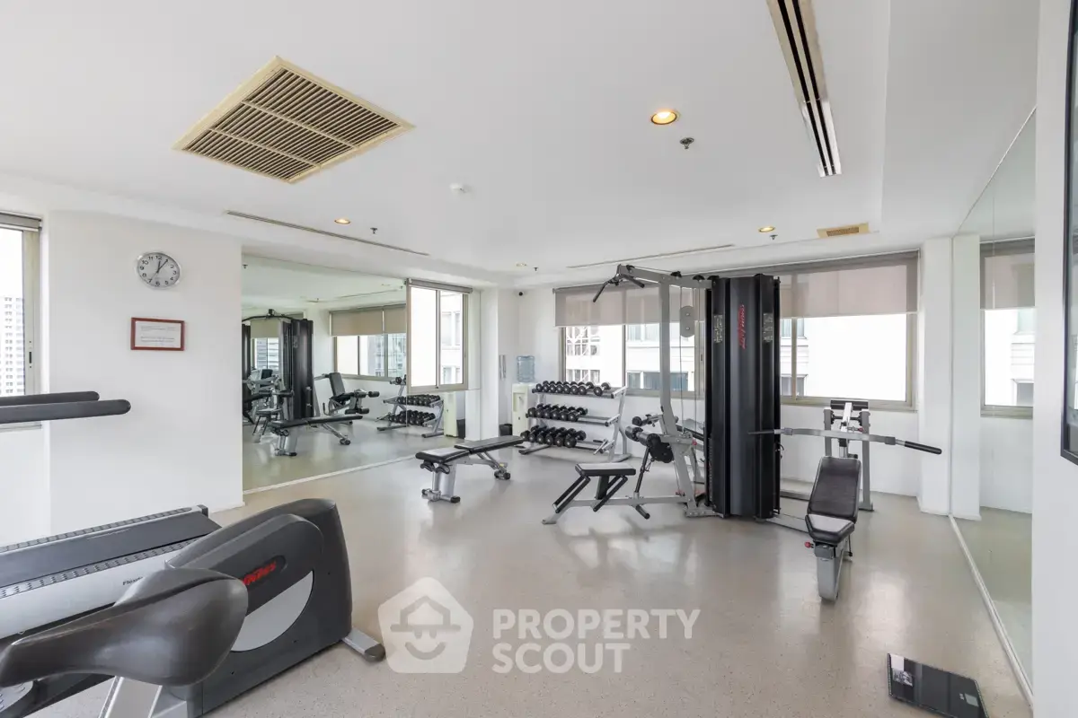Spacious modern gym with state-of-the-art equipment and large windows offering city views.
