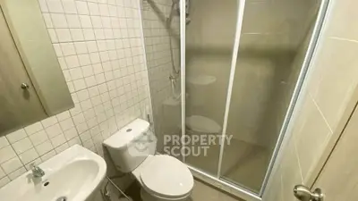 Compact bathroom with shower enclosure and modern fixtures in a cozy apartment.