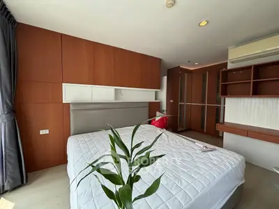 Modern bedroom with built-in wooden storage and large window for natural light.