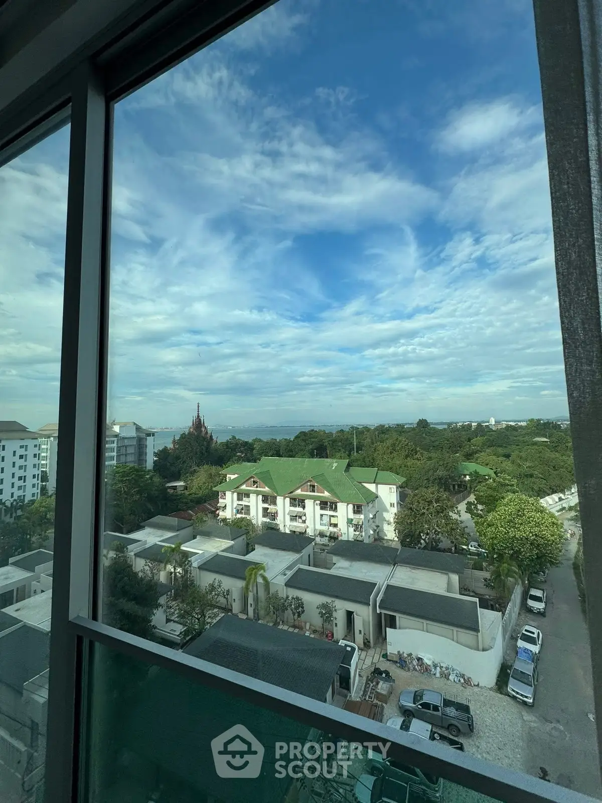Stunning view from high-rise window overlooking lush greenery and residential area.