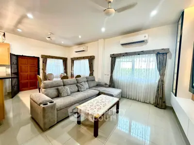 Spacious living room with modern decor and natural light, featuring a comfortable sofa and elegant curtains.