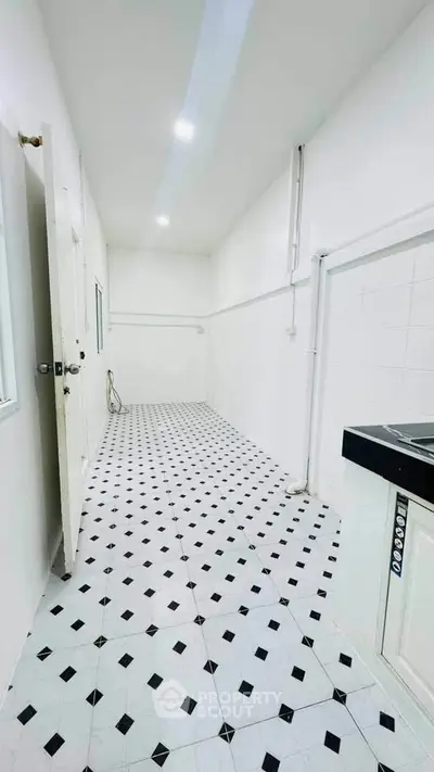 Spacious white tiled kitchen with modern fixtures and ample lighting