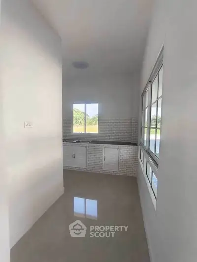 Bright kitchen with white cabinets and large window offering scenic views.