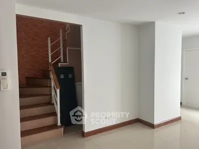 Spacious and bright living area with elegant wooden staircase and modern white walls, perfect for family gatherings and stylish living.
