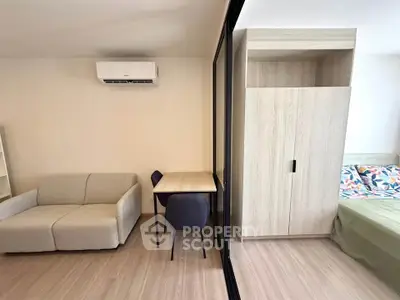 Modern studio apartment with sleek furniture and air conditioning, featuring a cozy living area and a comfortable bed.