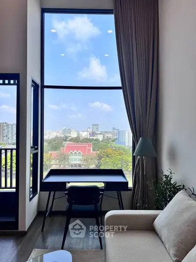 Modern living room with large window offering stunning city view, elegant furniture, and natural light.