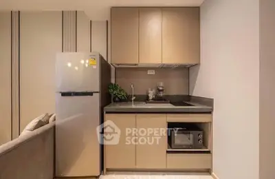 Modern compact kitchen with sleek cabinetry and appliances in a stylish apartment.