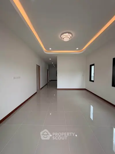Spacious modern living room with elegant ceiling lighting and glossy tiled floors.