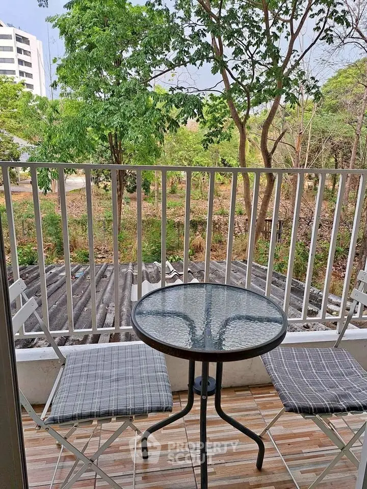 Charming balcony with cozy seating and lush green view, perfect for relaxation.