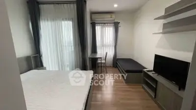 Modern bedroom with wooden flooring, featuring a bed, TV, and study area with natural light.
