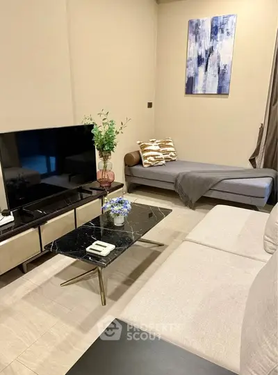 Modern living room with stylish decor and sleek furniture, featuring a large TV and elegant coffee table.