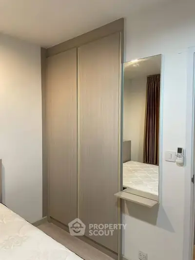 Modern bedroom with sleek sliding wardrobe and wall-mounted mirror