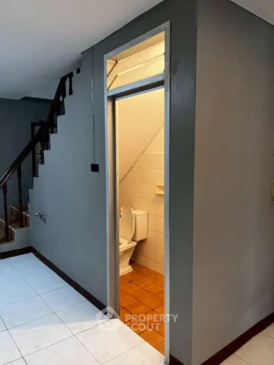 Compact under-staircase bathroom with tiled flooring and modern design.