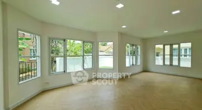 Spacious corner unit living room with large windows and wooden flooring.