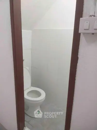 Compact bathroom with basic white toilet and tiled walls, ideal for small spaces.