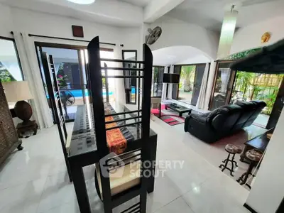Spacious open-plan living and dining area with pool view, modern furniture, and natural light.