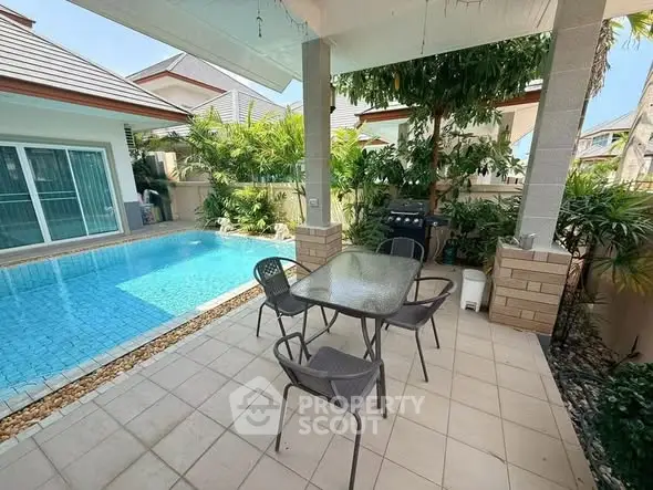 Charming patio with poolside view and lush greenery, perfect for outdoor relaxation and entertainment.