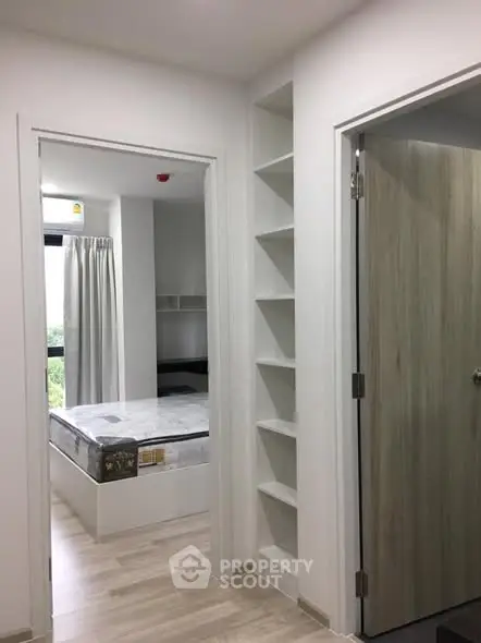 Modern apartment interior with bedroom and storage shelves, featuring minimalist design and natural light.