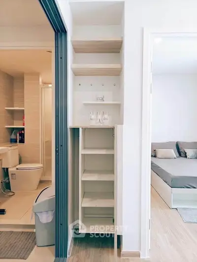 Modern apartment interior with bathroom and bedroom view, featuring sleek storage solutions and contemporary design.