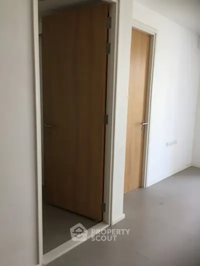 Minimalist interior hallway with wooden doors and white walls in modern apartment.