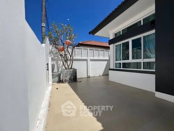 Modern exterior view of a stylish home with spacious patio and large windows under a clear blue sky.
