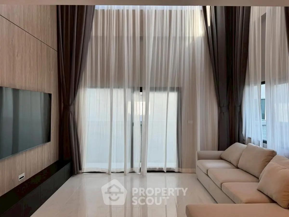 Luxurious living room with high ceilings, elegant curtains, and modern furnishings.