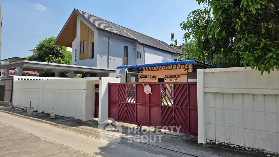 Modern two-story house with sleek design and gated entrance in a suburban neighborhood.