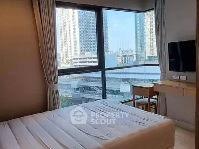 Modern bedroom with large windows offering stunning city views in a high-rise apartment.