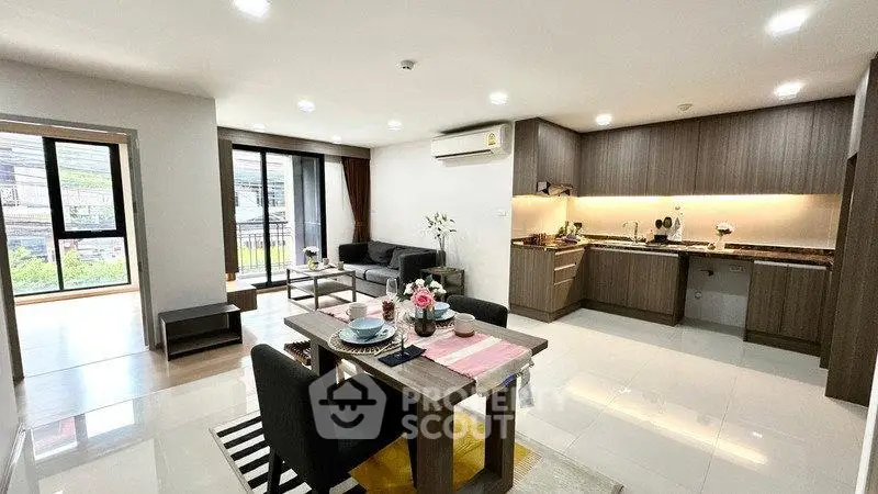 Spacious modern living room with open kitchen and dining area, featuring sleek design and ample natural light.