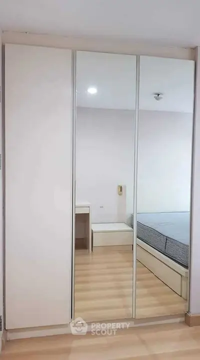 Modern bedroom with mirrored wardrobe and wooden flooring