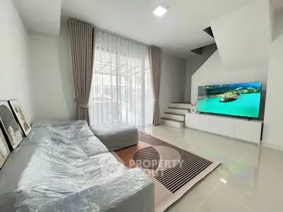Modern living room with sleek furniture and large TV, featuring elegant curtains and stylish decor.