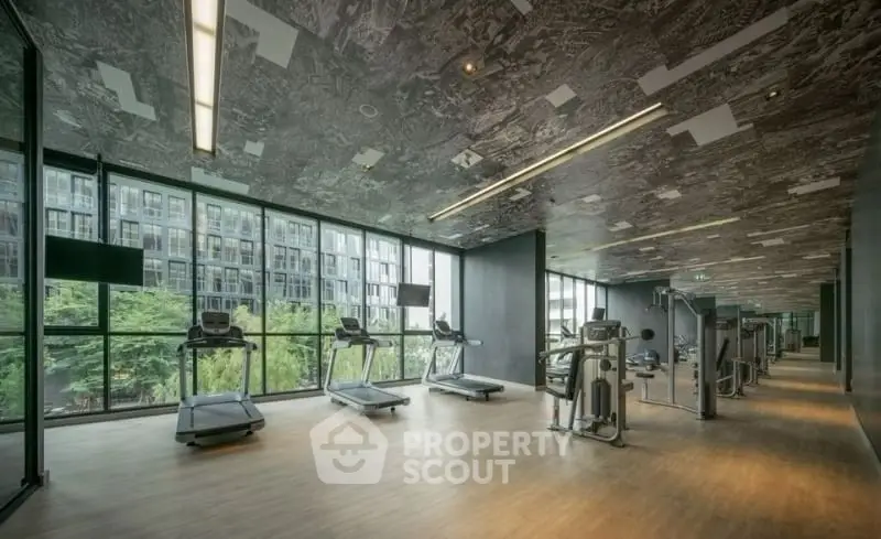 Spacious modern gym with large windows and city view in luxury building.