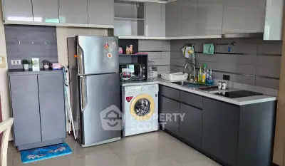 Modern kitchen with sleek cabinets, stainless steel fridge, and built-in washing machine.