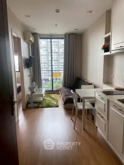 Modern studio apartment with open layout, featuring a cozy living area and kitchen, overlooking cityscape.
