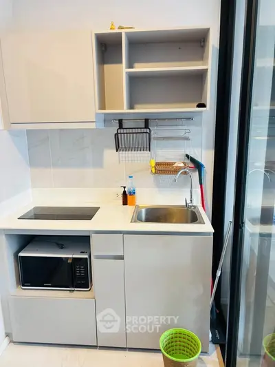 Modern compact kitchen with sleek cabinetry and built-in microwave, ideal for urban living.