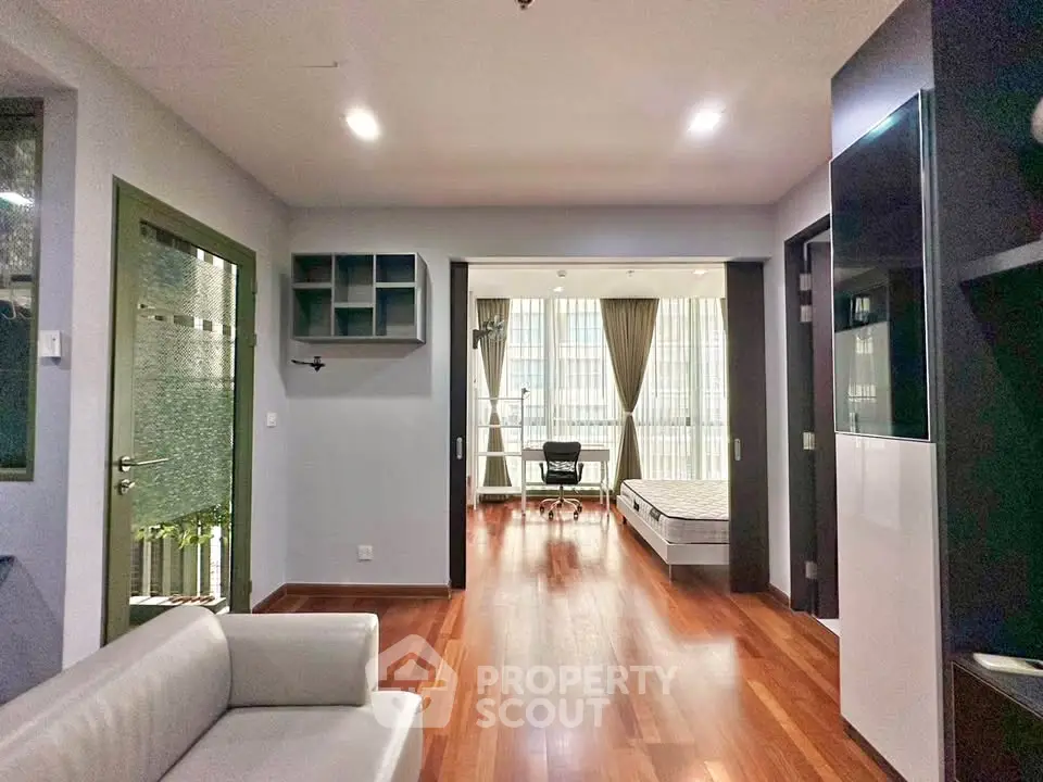 Spacious modern apartment with open layout and wooden flooring, featuring a cozy living area and a bright bedroom.