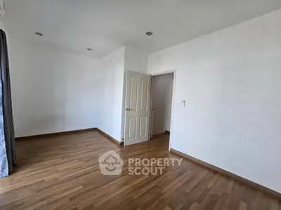 Spacious empty room with wooden flooring and white walls, ideal for customization.