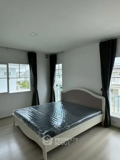 Spacious bedroom with large windows and modern decor in a bright, airy home.