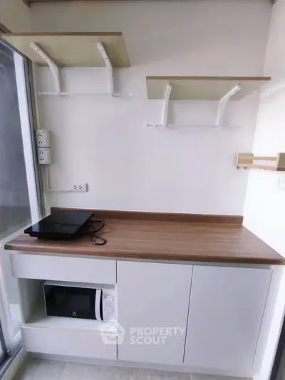 Modern kitchen with sleek countertop, microwave, and electric stove in a compact layout.