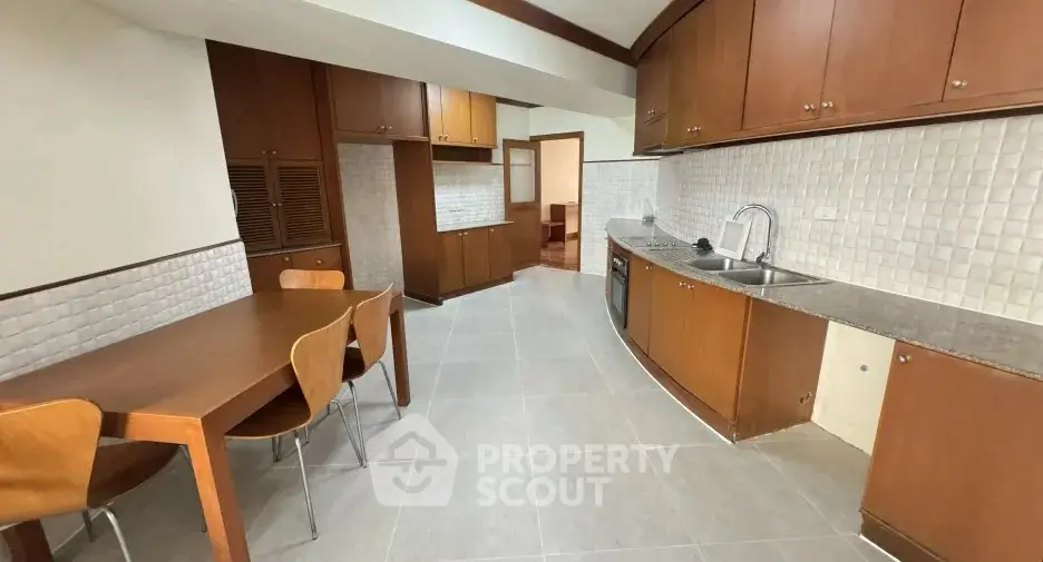 Spacious kitchen with wooden cabinets and dining area in modern apartment