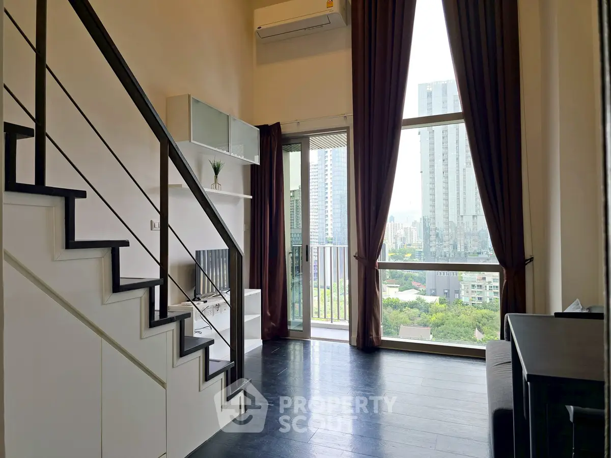 Modern loft apartment with large windows and city view, featuring sleek staircase and stylish decor.