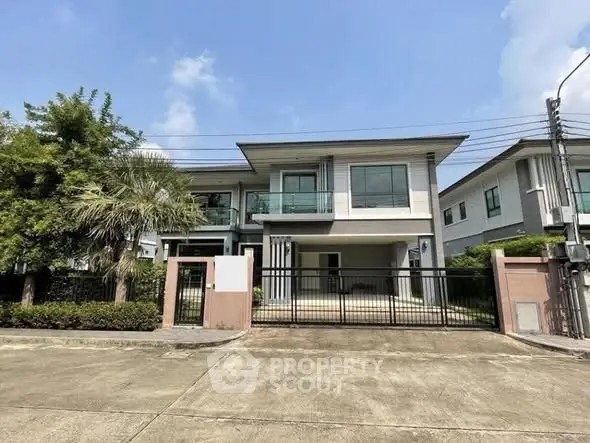 Modern two-story house with sleek design and spacious driveway in a suburban neighborhood.
